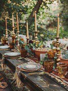 a long table with candles and plates on it is set for an outdoor dinner party