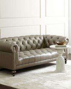 a leather couch sitting on top of a rug next to a white table and chair