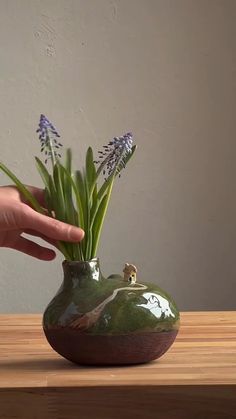 a hand holding a vase with flowers in it