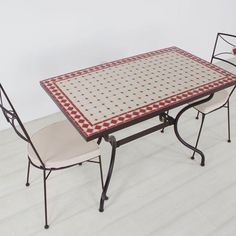 a table and two chairs sitting on top of a hard wood floored floor in front of a white wall