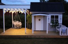 a small white shed with a porch and swing set