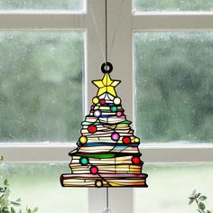 a stained glass christmas tree hanging from a window