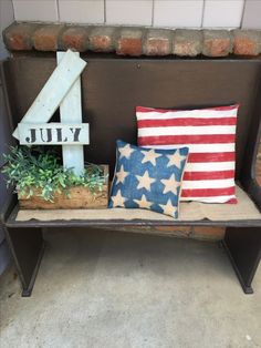 an old bench with two pillows and a sign