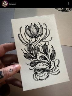 a person holding up a piece of paper with some ink on it and flowers in the middle