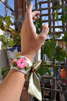 a woman's hand with a pink flower on it and a green ribbon around the wrist