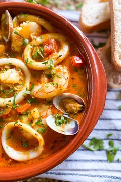 a bowl of seafood soup with bread on the side