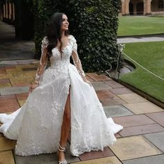 a woman in a white wedding dress standing on a brick walkway with her legs spread out