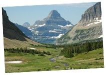 the mountains are covered in snow and green grass, with a stream running between them