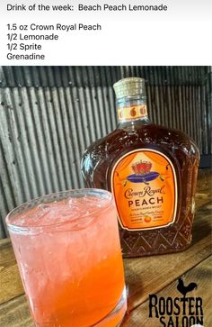 a bottle of peach lemonade next to a glass filled with orange liquid on top of a wooden table