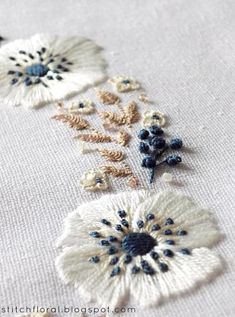 some white flowers and blue beads are on a table cloth with black trimmings