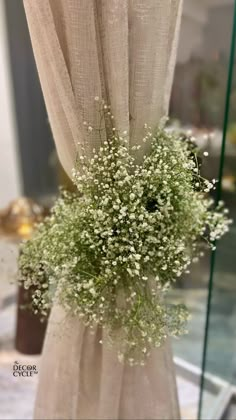 baby's breath in front of a window with the curtain open and flowers hanging from it