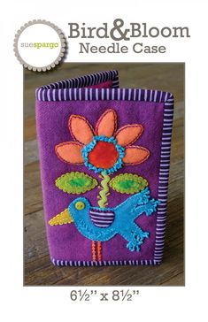 a purple bag with flowers and birds on it, sitting on top of a wooden table