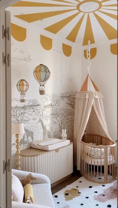 a baby's room decorated in white and yellow with hot air balloons on the wall