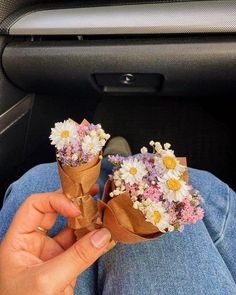 someone is holding flowers in their hand while sitting in the car