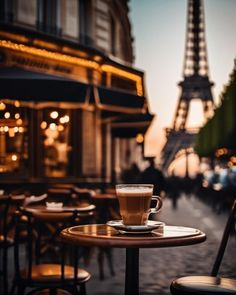 a cup of coffee on a table in front of the eiffel tower at dusk