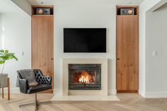 a living room with a fireplace and television mounted on it's wall next to a chair