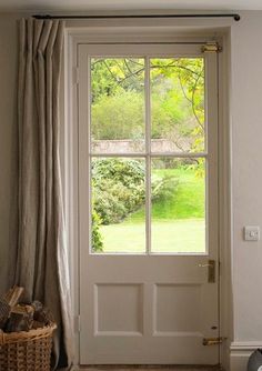 an open door with a basket on the floor next to it in front of a window