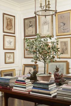 there is a table with many books and pictures on the wall in this living room