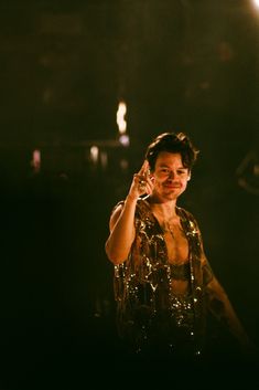 a man standing in the dark talking on a cell phone while holding his hand up to his ear