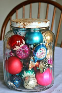 a glass jar filled with ornaments on top of a table