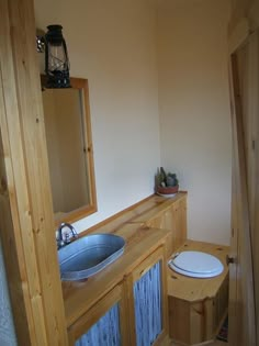 a bathroom with a toilet, sink and mirror on the wall next to wooden cabinets