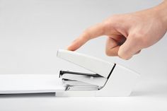 a person's hand is touching the edge of a white laptop computer with its lid open