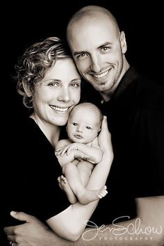 a man and woman holding a baby in their arms