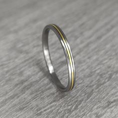 a thin silver and gold ring on a gray surface