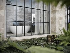 a bath tub sitting in the middle of a lush green forest next to a window