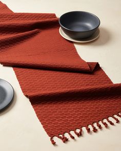 a red table runner next to a bowl and plate