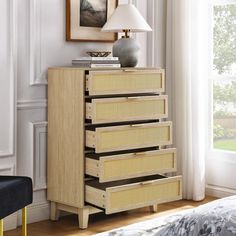 a dresser with drawers and a lamp on top of it in a room next to a window