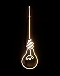 a neon light bulb hanging from the side of a black wall with a white cord attached to it