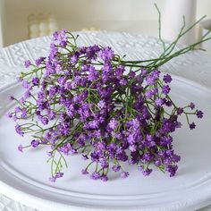 purple flowers are sitting on a white plate