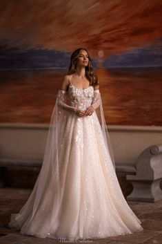 a woman in a wedding dress standing next to a wall with a painting on it