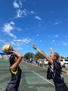 two girls are playing with a ball on a court while people watch from the sidelines