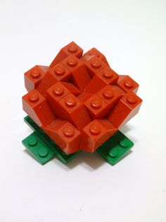 an orange flower made out of legos on a white surface