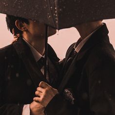 two people standing under an umbrella in the rain with their faces close to each other