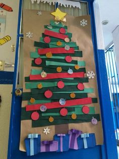 a christmas tree made out of strips of paper on a blue door with snowflakes