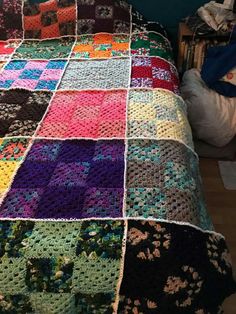 a crocheted bed spread made with multicolored granny afghans on top of a wooden floor