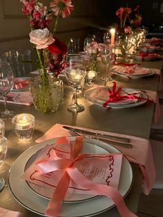 the table is set with pink and white flowers, silverware, candles, and napkins