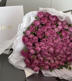 a bouquet of pink roses sitting on top of a table next to a white box