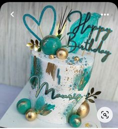 a white and blue birthday cake with gold decorations