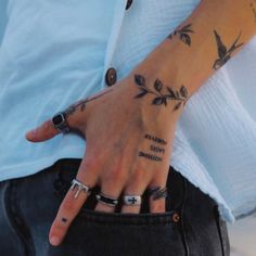 a man with tattoos on his hand and ring around his finger, holding onto the other hand