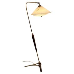 a floor lamp with a white shade on it's side and a wooden stick in the middle