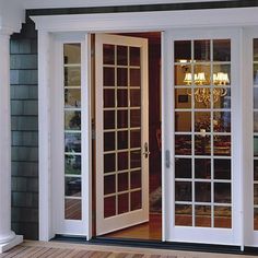 the front door to a house with glass doors and chandelier hanging from it's side