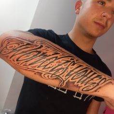 a man with a tattoo on his arm that reads, the words are written in cursive writing