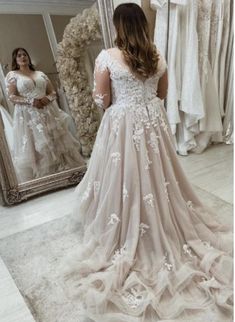 a woman standing in front of a mirror wearing a wedding dress