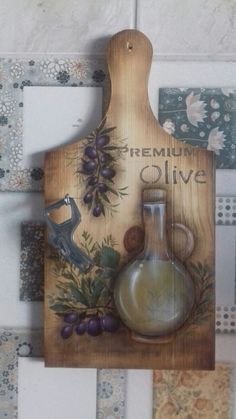 a wooden cutting board with an olive oil bottle and grapes painted on the side, surrounded by tiles