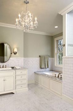 a large bathroom with two sinks, tub and chandelier