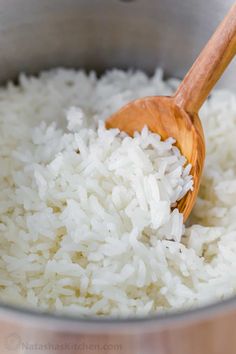 rice is being stirred in a pot with a wooden spoon